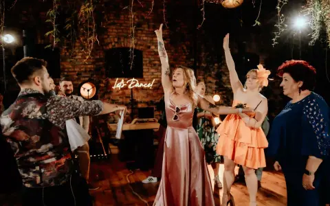 Nowoczesne oczepiny w blasku neonu "Let's Dance!". Kobiety w sukniach unoszą ręce, celebrując radosny moment.