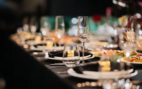 Elegancko nakryty stół weselny z kieliszkami i talerzykami. Zastanawiasz się, ile za talerzyk na wesele?