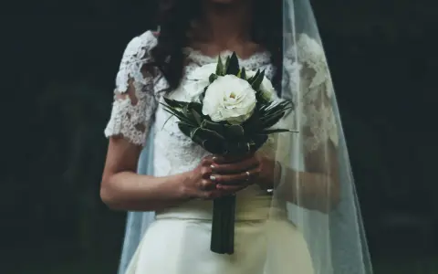 Panna młoda z bukietem białych róż, w welonie i koronkowej sukni. W myślach słyszy "Ave Maria po polsku na ślub tekst".