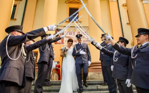 Para młoda przechodzi pod łukiem z szabel, tworząc tradycyjne wejście do kościoła ślub.