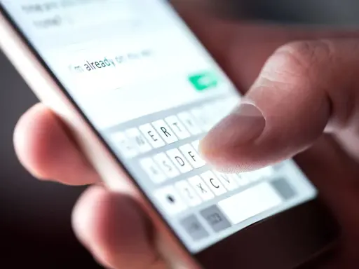 Palec pisze na klawiaturze telefonu: "Już w drodze". Potwierdzenie przybycia na wesele sms.