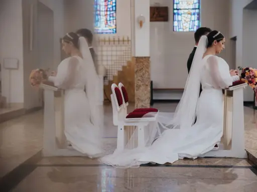 Para młoda klęczy przy ołtarzu. W tle witraże. Czyżby to były przesądy ślubne dla pana młodego?