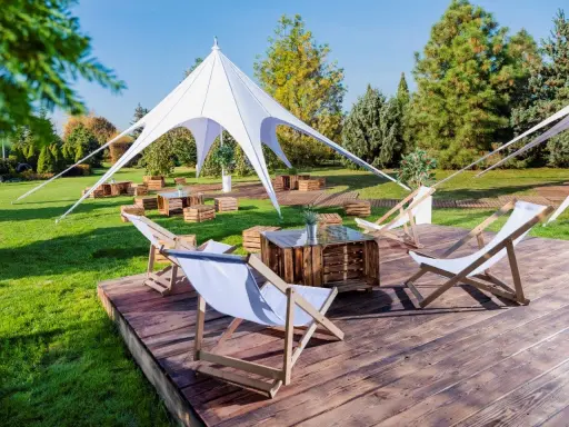 Idealna strefa chillout: leżaki, drewniane skrzynki i biały namiot tworzą relaksującą atmosferę na trawie.