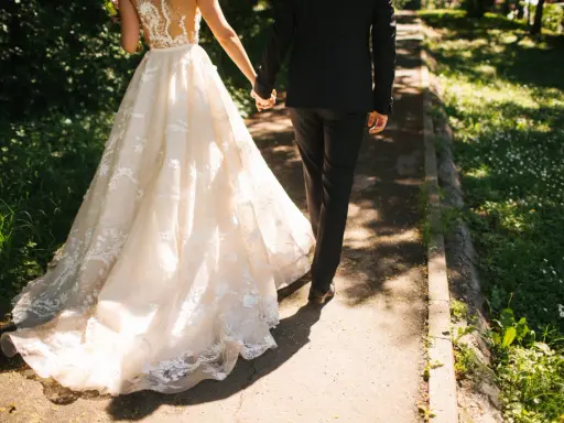Para zjawiskowa suknia ślubna i elegancki garnitur idący ręka w rękę. Jak zareagować na zawiadomienie o ślubie?