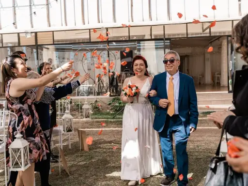 Płatki róż sypią się na parę młodą podczas uroczystości. Mimo że to slub zima, słońce świeci, a goście rzucają kwiaty.