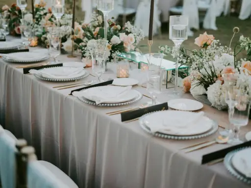 Eleganckie bukiety na stół weselny z goździków, róż i gipsówki, tworzą romantyczną atmosferę.