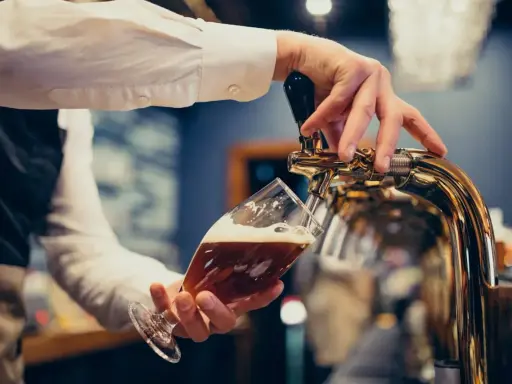 Barman nalewa piwo do kieliszka. Zastanawiasz się, ile piwa na poprawiny? To piwo wygląda pysznie!
