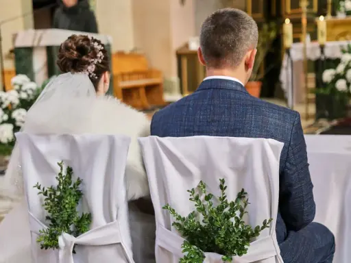 Para młoda siedzi w kościele. Krzesła ozdobione zielonymi gałązkami. Kto nie może być świadkiem na ślubie kościelnym?