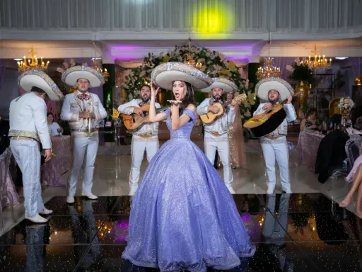 Dziewczyna w fioletowej sukni i mariachi śpiewają, tworząc atmosferę pełną radości i być może sprośnych przyśpiewek.