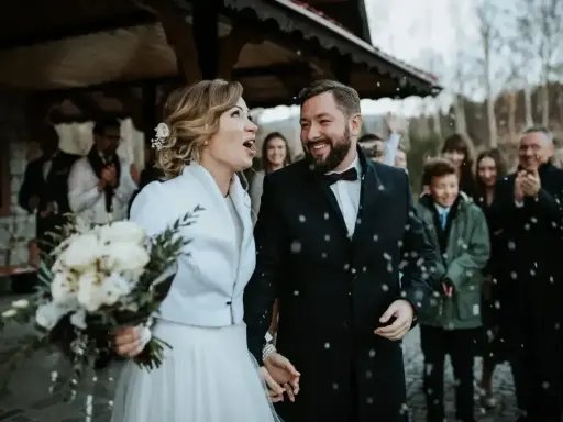 Para młoda wychodzi z kościoła, obsypana konfetti. Mimo że to najgorszy miesiąc na ślub, ich uśmiechy rozświetlają zimny dzień.