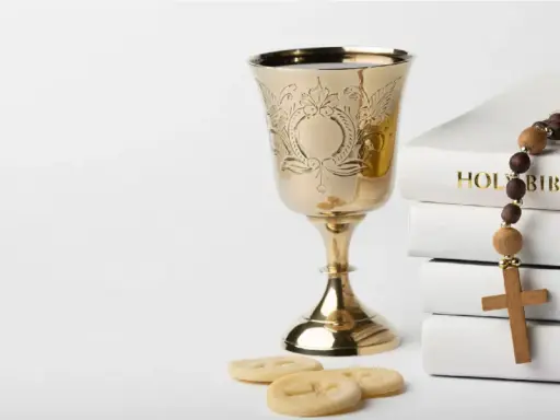 Złoty kielich, hostie, różaniec i Biblia. Symbolika sakramentów, od chrztu do ślubu, przygotowująca do życia w wierze.
