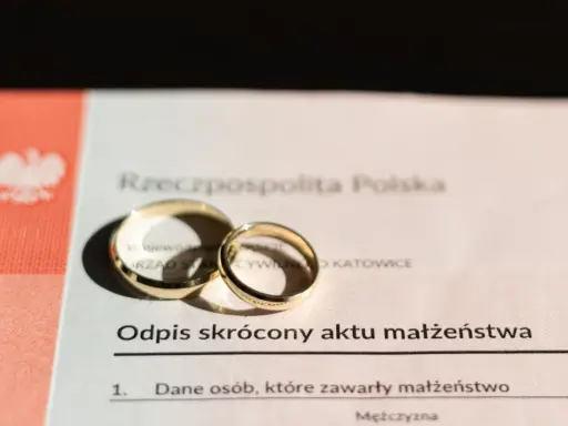 Złote obrączki na odpisie skróconym aktu małżeństwa po ślubie cywilnym. Dokument z Urzędu Stanu Cywilnego w Katowicach.