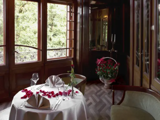 Romantyczna kolacja przy świecach i płatkach róż – tak powinny wyglądać zaręczyny. Kosz czerwonych róż i widok na zieleń dodają uroku.