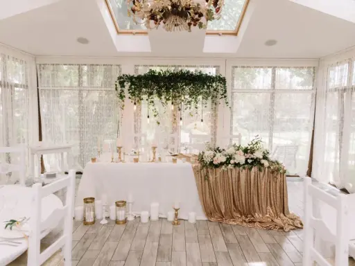 Elegancka sala weselna z białymi krzesłami i stołem pary młodej ozdobionym złotymi cekinami i kwiatami. Wspaniałe kolory na wesele.
