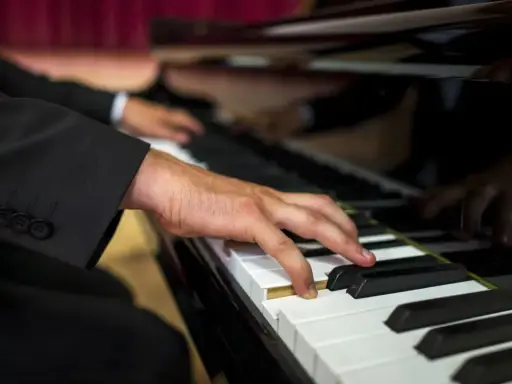Dłoń muzyka w garniturze gra na fortepianie. Zastanawiasz się, ile bierze organista za ślub?