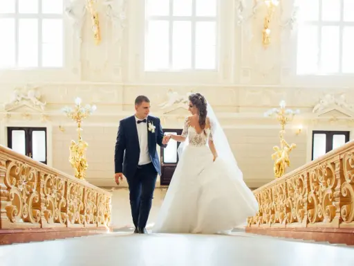 Para Młoda idzie po schodach ozdobionych bogatą dekoracją schodów na wesele.