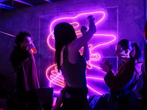 Ludzie tańczą w rytm energicznych piosenek do tańca, w otoczeniu fioletowego neonu.