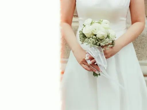 Elegancki bukiet ślubny glamour z białych róż i gipsówki, ozdobiony białą wstążką.