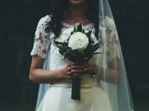 Panna młoda z bukietem białych róż, w welonie i koronkowej sukni. W myślach słyszy "Ave Maria po polsku na ślub tekst".