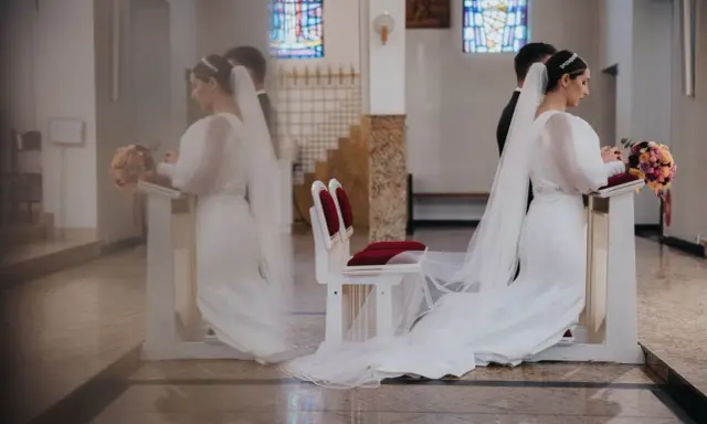 Para młoda klęczy przy ołtarzu. W tle witraże. Czyżby to były przesądy ślubne dla pana młodego?