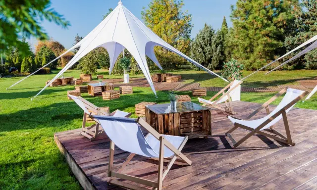 Idealna strefa chillout: leżaki, drewniane skrzynki i biały namiot tworzą relaksującą atmosferę na trawie.