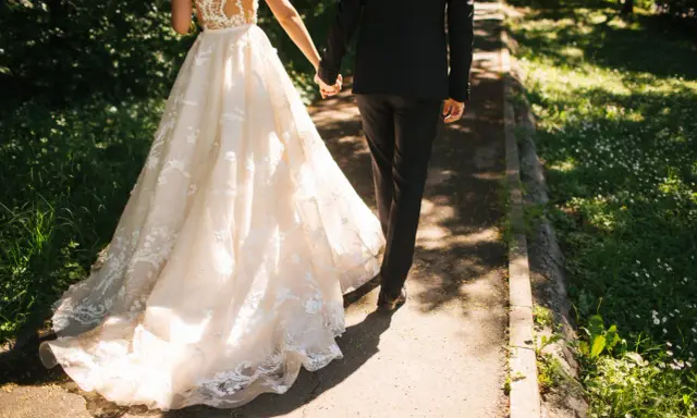 Para zjawiskowa suknia ślubna i elegancki garnitur idący ręka w rękę. Jak zareagować na zawiadomienie o ślubie?
