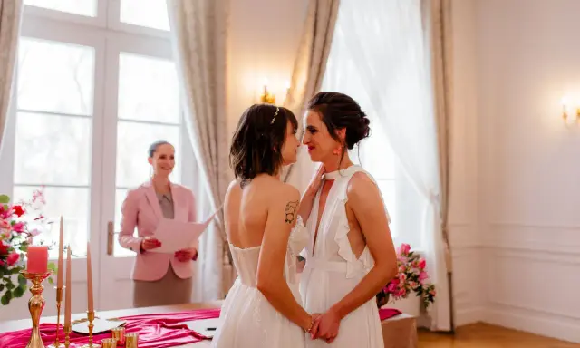 Dwie kobiety w białych sukniach ślubnych patrzą sobie w oczy podczas ceremonii. To piękny ślub homoseksualny.