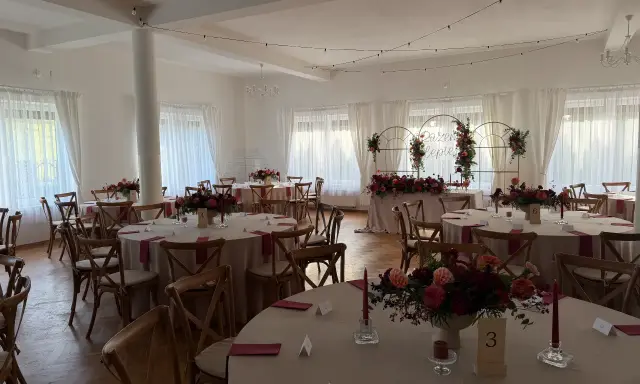 Elegancka sala weselna z okrągłymi stołami, kwiatami i świecami. Wesele co trzeba wiedzieć, by wszystko było idealne.