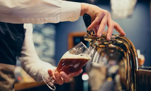 Barman nalewa piwo do kieliszka. Zastanawiasz się, ile piwa na poprawiny? To piwo wygląda pysznie!