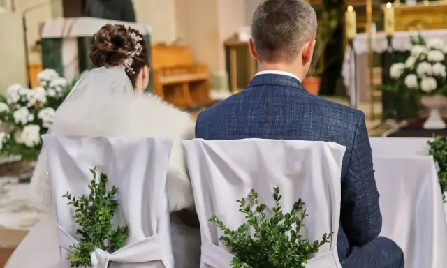Para młoda siedzi w kościele. Krzesła ozdobione zielonymi gałązkami. Kto nie może być świadkiem na ślubie kościelnym?