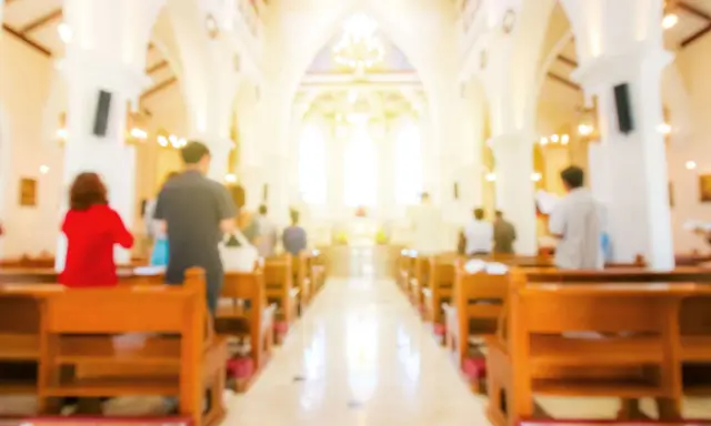 Wnętrze kościoła, ludzie siedzą w ławkach. Czy nauki przedmałżeńskie są obowiązkowe? To pytanie zadają sobie narzeczeni.