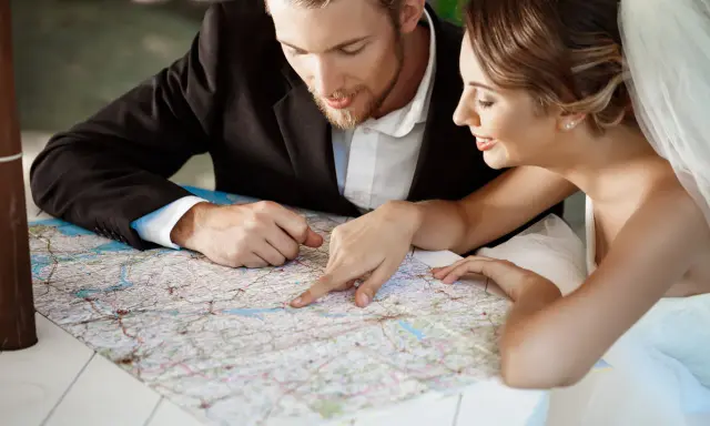 Młoda para, przygotowująca się do ślubu, planuje podróż poślubną, studiując mapę.
