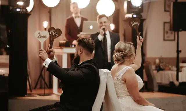 Para zabawy podczas wesela. Ona trzyma tabliczkę "Żona", on "Mąż". Prowadzący zadaje pytania w ramach testu małżeńskiego.