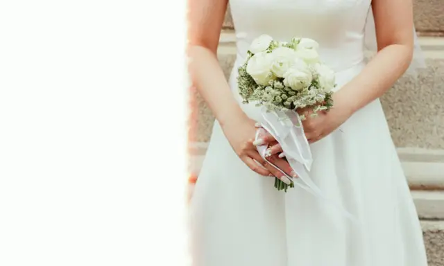 Elegancki bukiet ślubny glamour z białych róż i gipsówki, ozdobiony białą wstążką.