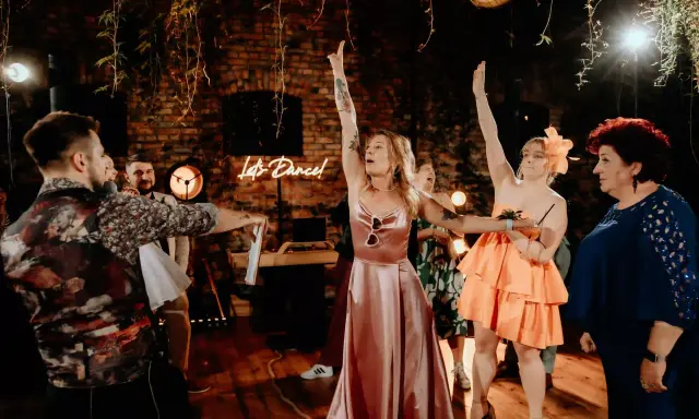 Nowoczesne oczepiny w blasku neonu "Let's Dance!". Kobiety w sukniach unoszą ręce, celebrując radosny moment.