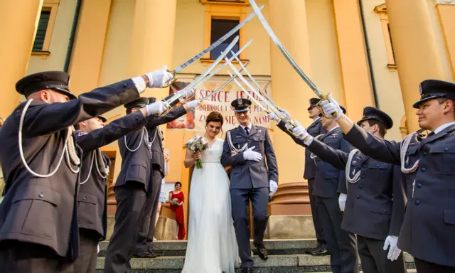 Para młoda przechodzi pod łukiem z szabel, tworząc tradycyjne wejście do kościoła ślub.