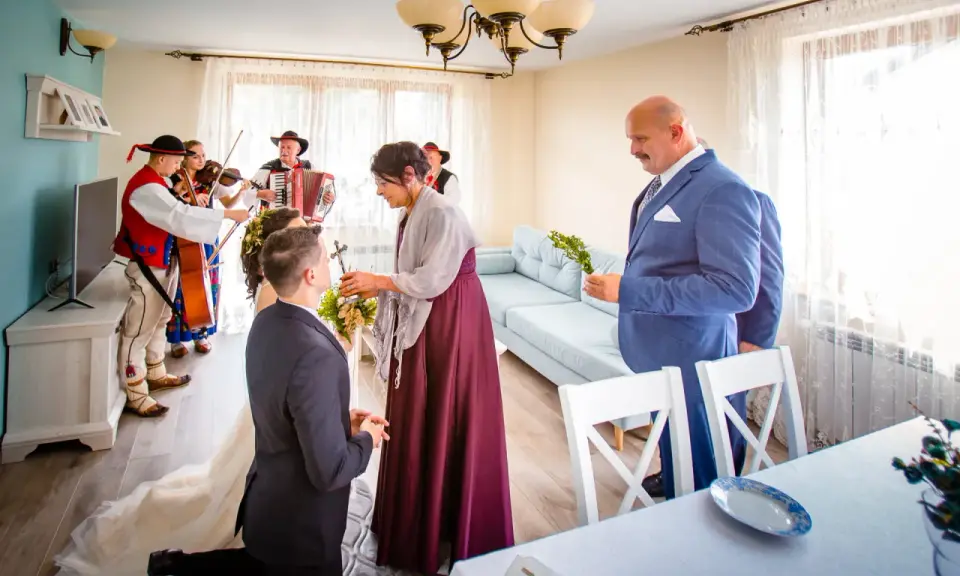 Wzruszający moment błogosławieństwa matki chrzestnej dla pary młodej, przy akompaniamencie kapeli góralskiej.