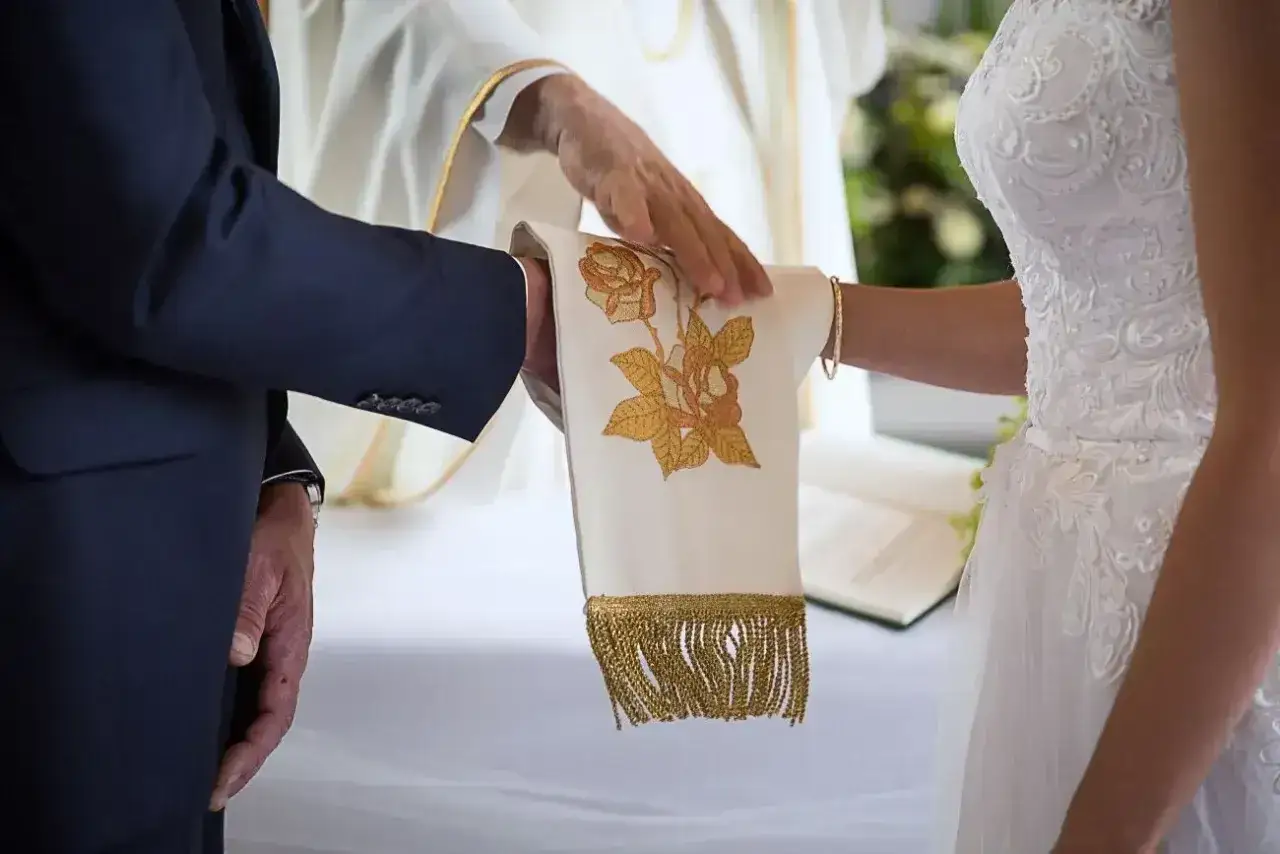 Ceremonia ślubu kanonicznego: dłoń księdza błogosławi parę młodą, która trzyma ozdobną stułę.