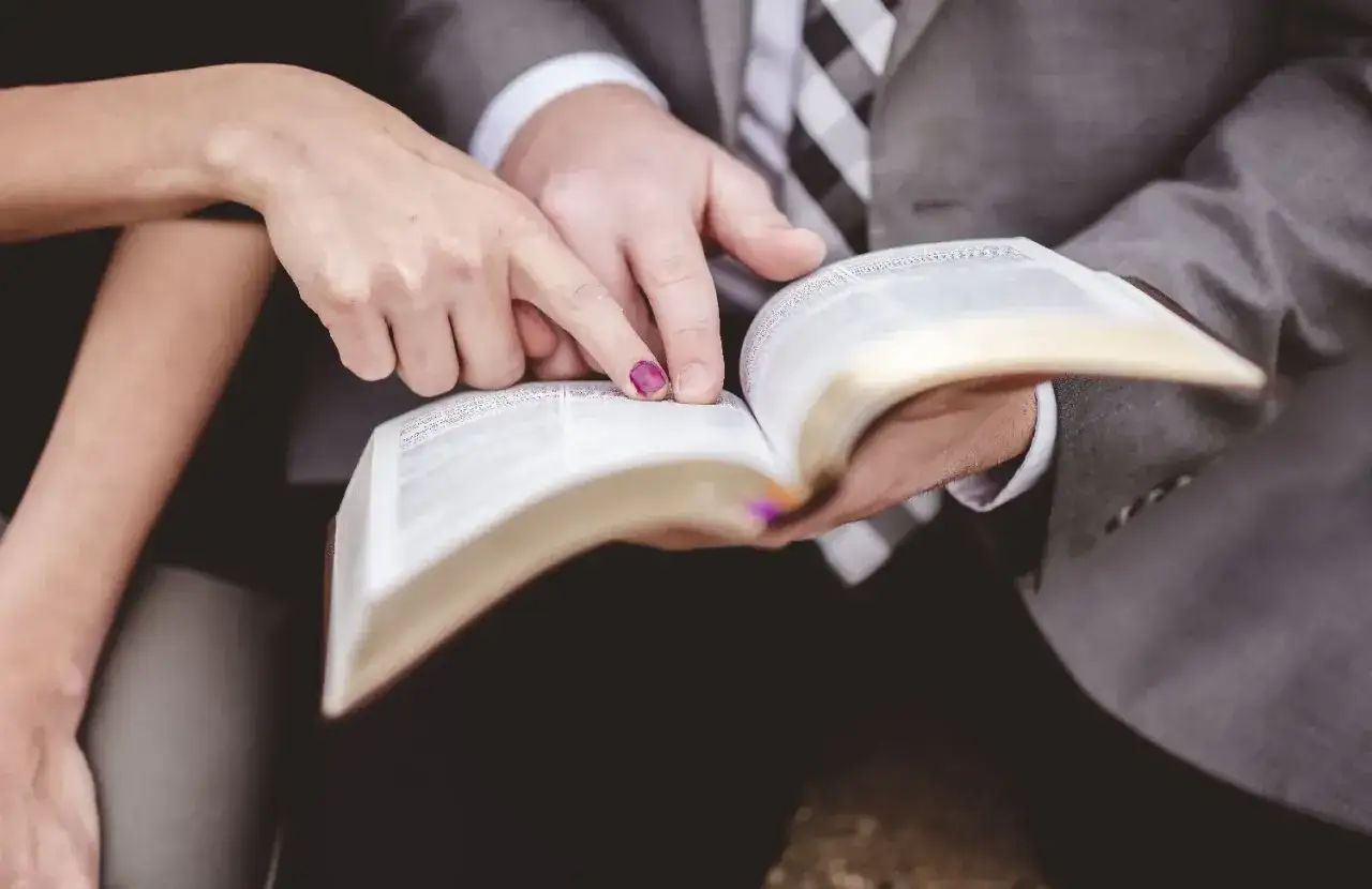 Dłonie pary wskazują na tekst w Biblii, przygotowując się do pierwszego czytania na ślub.
