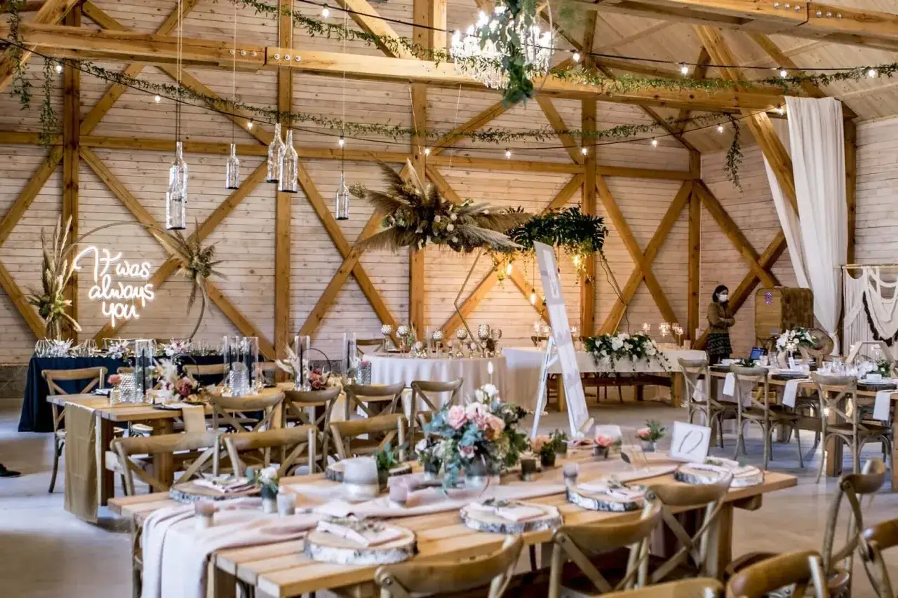 Elegancka sala weselna z drewnianymi belkami, girlandami świateł i neonem