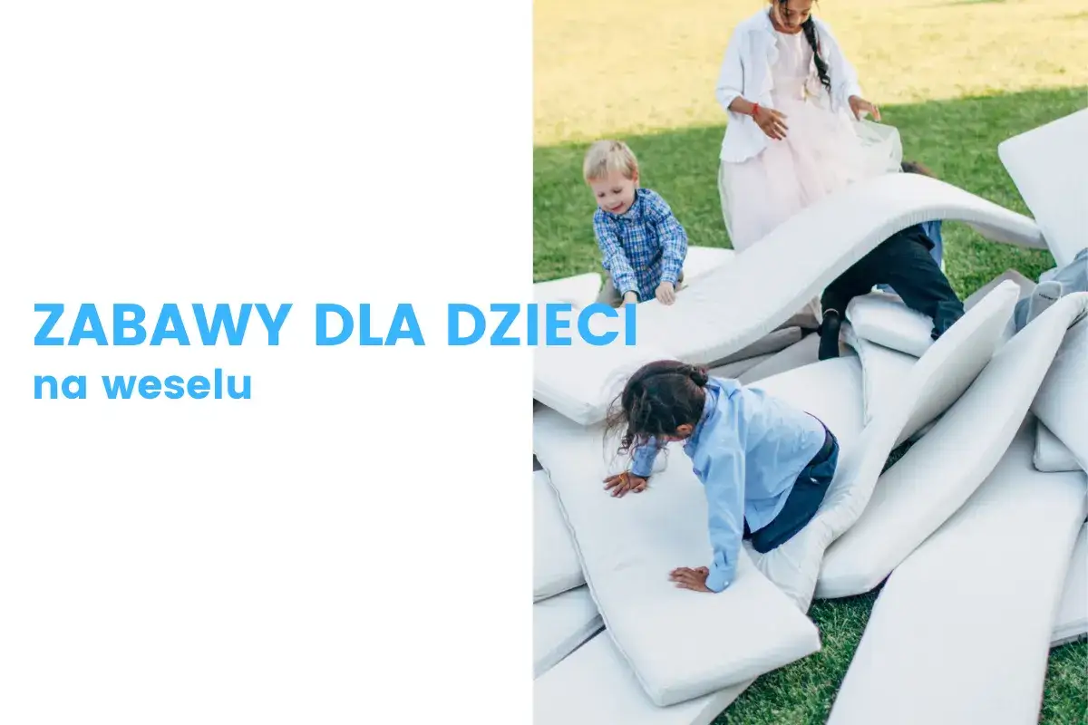 Radosne dzieci bawią się na stosie materacy na trawie, tworząc własne przygody podczas wesela.