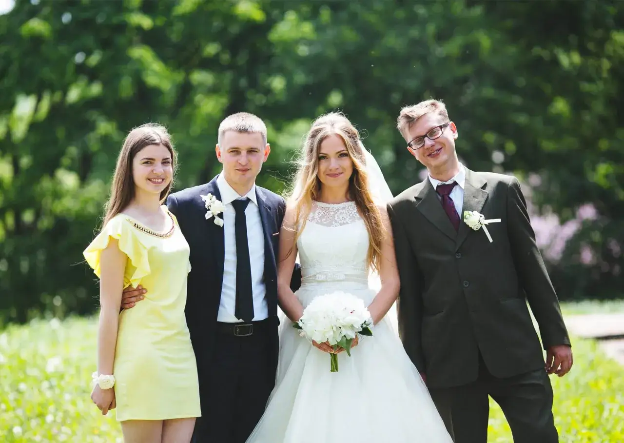 Para młoda z druhnami i świadkiem po ślubie, w otoczeniu zieleni.