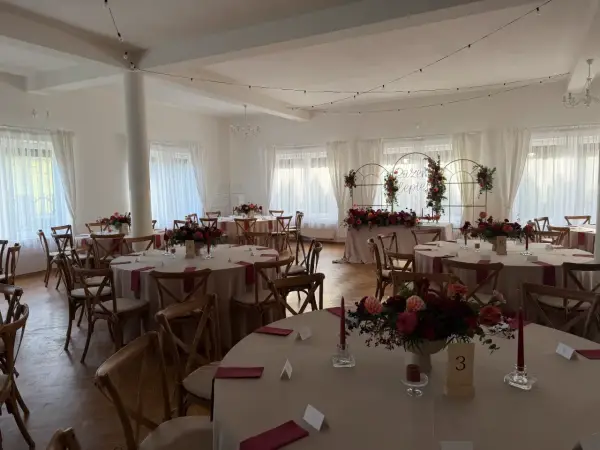 Elegancka sala weselna z okrągłymi stołami, kwiatami i świecami. Wesele co trzeba wiedzieć, by wszystko było idealne.