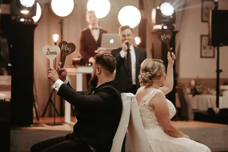 Para zabawy podczas wesela. Ona trzyma tabliczkę "Żona", on "Mąż". Prowadzący zadaje pytania w ramach testu małżeńskiego.
